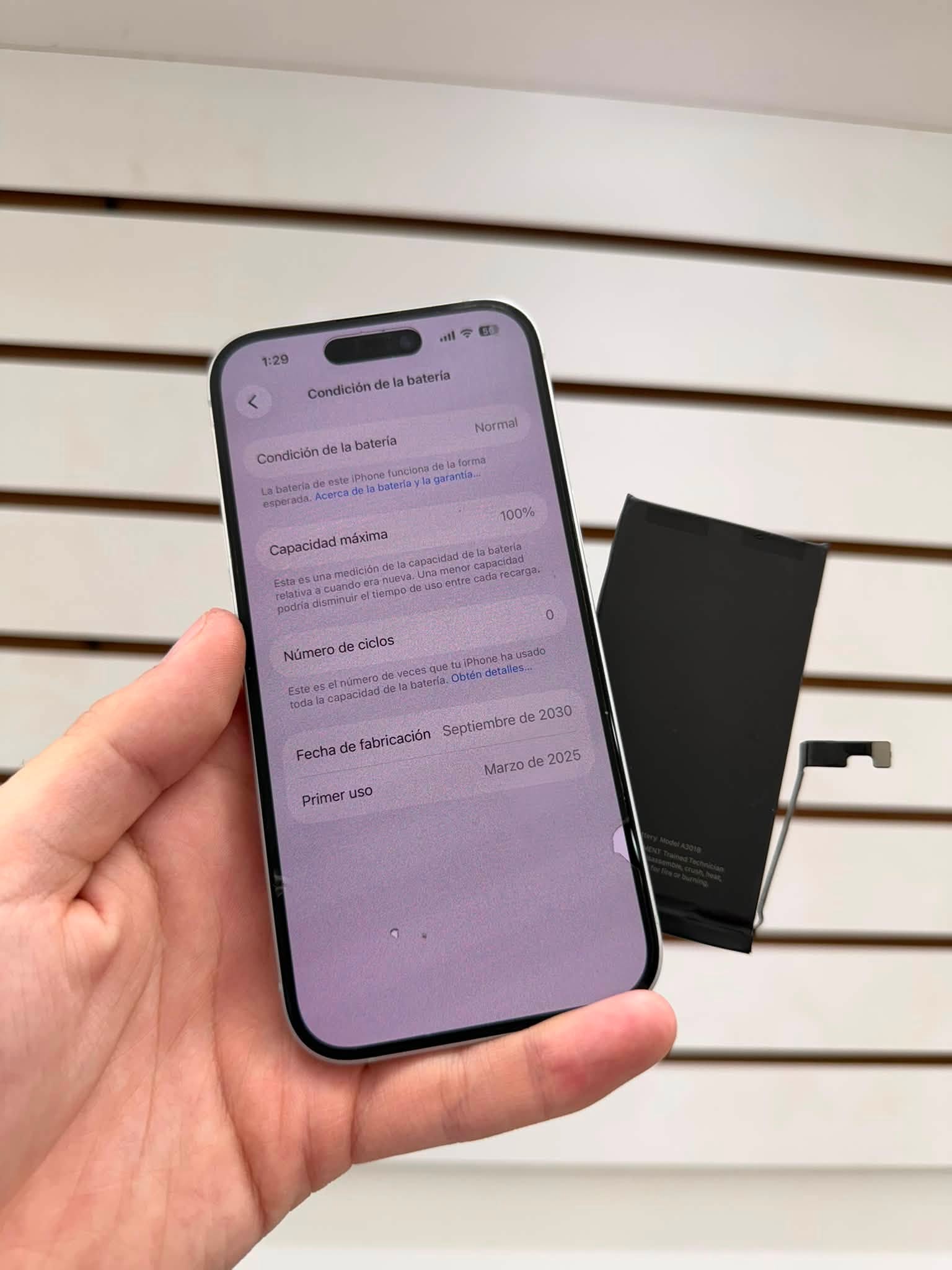 Celular con la condición de batería al 100 por ciento junto a la batería retirada en PHONITS