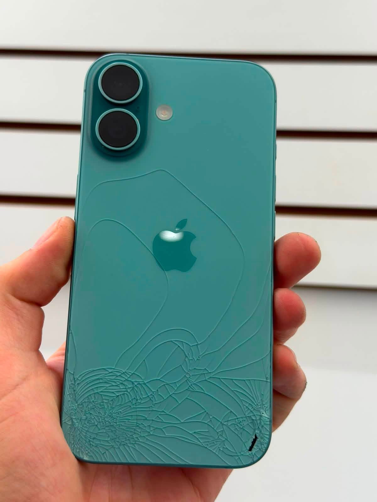 Celular con el cristal trasero fracturado antes de su reparación en PHONITS